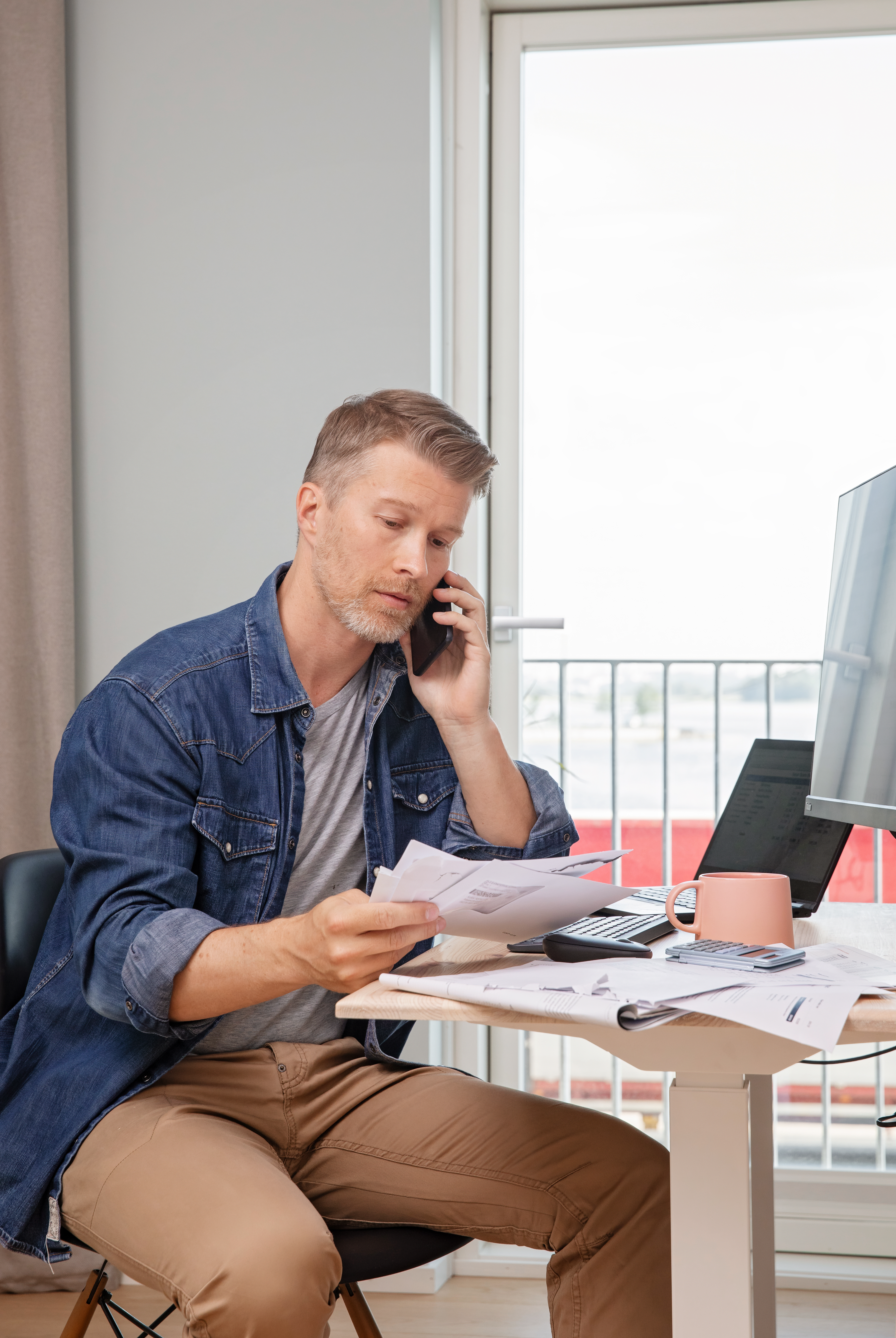 Two men sitting by a table with papers on it talking