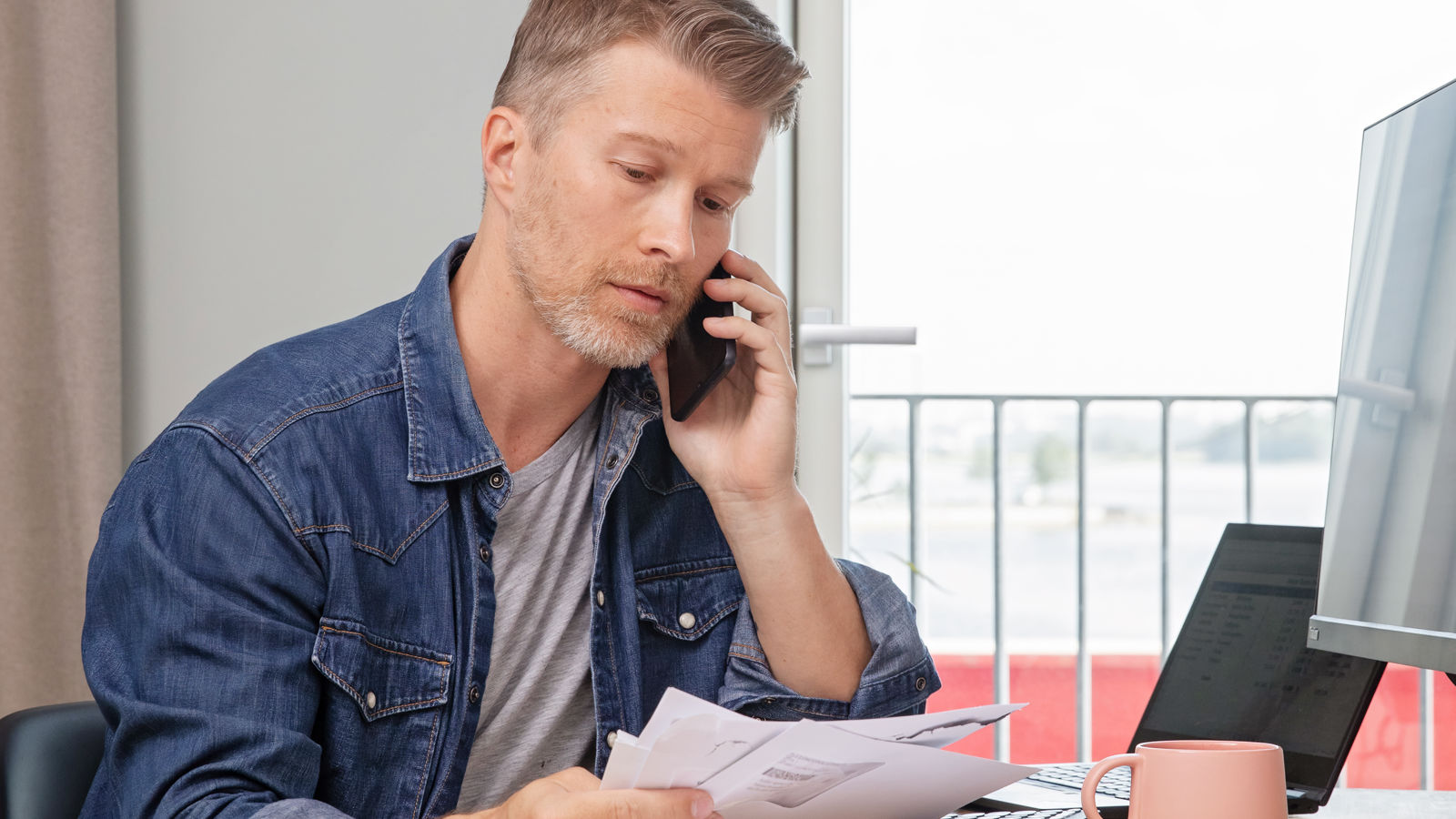Two men sitting by a table with papers on it talking